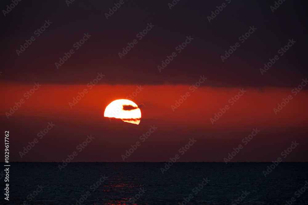 The red sun between the sea and the clouds The red sun between the sea and the clouds