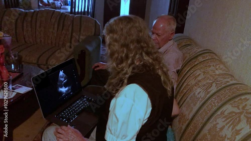 Senior brother and sister using laptop at home into living room for review of echocardiogram study of cardiac arrhythmia condition heartbeat