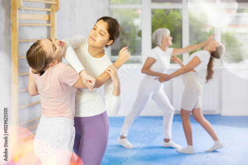 Young girl and woman train to perform effective blows and impact on pain points eyes groin while learning self-defense techniques. Lesson in presence of experienced instructor