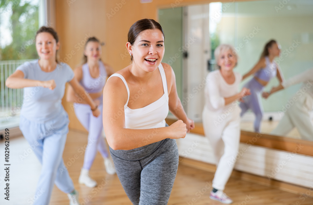 Fototapeta premium Excited positive women of different ages performing modern dancing exercises in school for adults