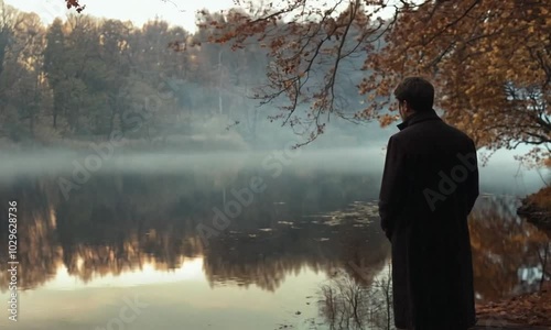 Pensive Man Standing by a Misty Lake in Autumn photo