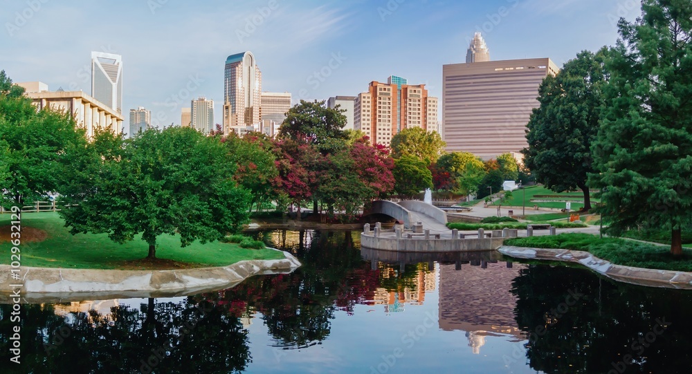 Fototapeta premium Pond in Marshall Park and downtown city skyline of skyscrapers at sunrise. Charlotte, North Carolina, United States.