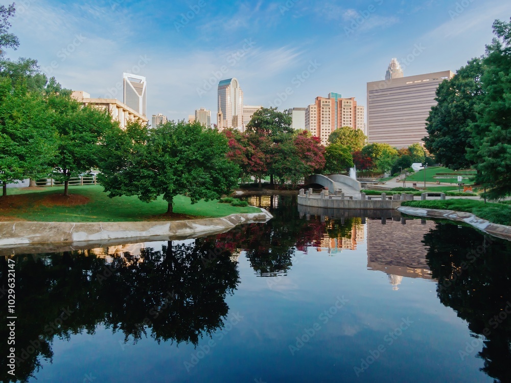 Obraz premium Pond in Marshall Park and downtown city skyline of skyscrapers at sunrise. Charlotte, North Carolina, United States.