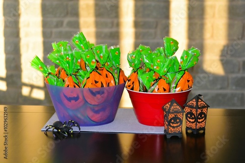 Fotografía Two bowls filled with pre-packaged bags of candy along with a big black plastic spider and black and orange lanterns wait for trick or treaters on Halloween