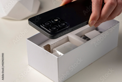 Unboxing a new smartphone. Female hands holding modern smartphone with blank screen. Online shopping, recent gadget concept