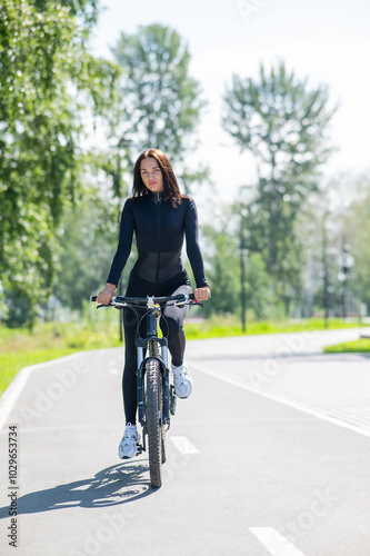 Caucasian woman riding a bike in a park. Vertical photo. 