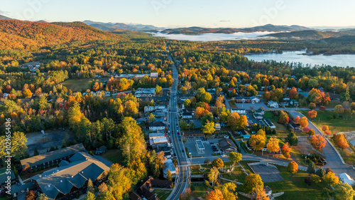 Fototapeta Naklejka Na Ścianę i Meble -  Aerial view of Schroon Lake, NY, with vibrant autumn colors, tree-lined streets, and surrounding Adirondack Mountains, showcasing the small town's scenic charm and peaceful lakeside setting.