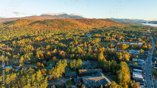 Aerial view of Schroon Lake, NY, with vibrant autumn colors, tree-lined streets, and surrounding Adirondack Mountains, showcasing the small town's scenic charm and peaceful lakeside setting. photo