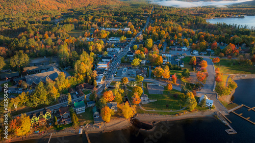 Aerial view of Schroon Lake, NY, highlighting the charming small town, vibrant autumn trees, and peaceful lakeside setting under the warm golden light of late afternoon. photo