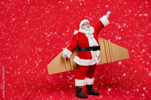 Full length photo of excited grey-hair elderly santa spaceman impressed by magic craft wings fly up hurry to eve wear cap hat isolated over red background