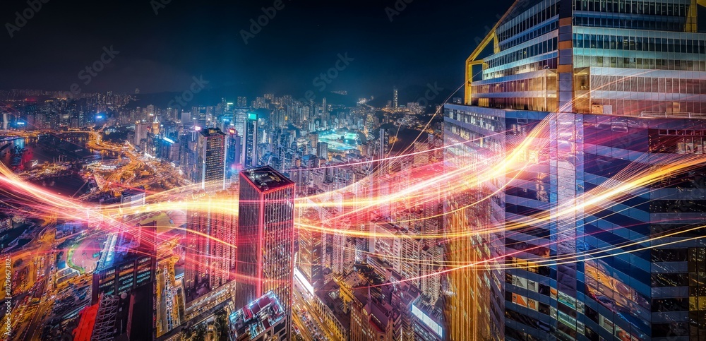 Aerial night view of a Hong Kong cityscape with glowing lights and skyscrapers, with streaks of light reflecting off the buildings.