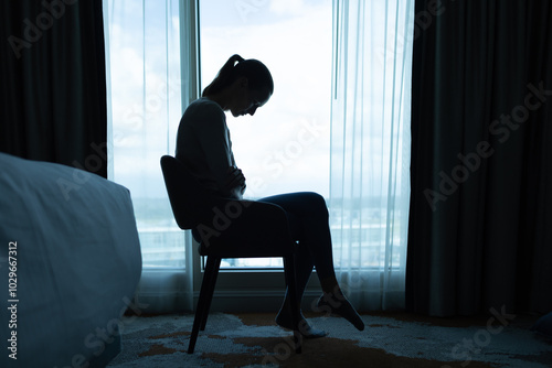 Young woman with head down sitting indoors feeling depressed, sad lonely 