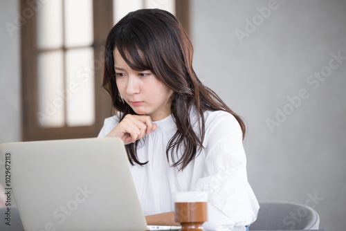 Profile of a troubled young woman thinking while looking at a computer.　