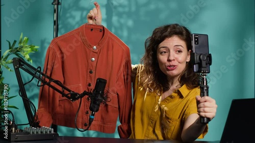 Wallpaper Mural Happy woman filming fashion vlog, holding jacket in hand, showing subscribers purchases she recently got. Internet show host presenting viewers new clothing acquisition, camera A Torontodigital.ca