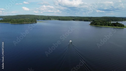 High aerial shows long wake behind small boat motoring on blue lake photo