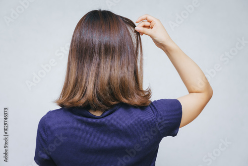 髪の毛の痛みを気にする女性 A woman concerned about hair damage