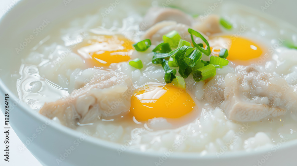Creamy rice porridge with tender chicken pieces and fresh green onions, topped with soft boiled eggs, creating comforting and nutritious meal Creamy rice porridge with tender chicken pieces and fresh green onions, topped with soft boiled eggs, creating comforting and nutritious meal
