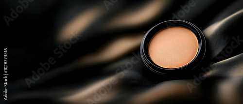 A jar of creamy makeup on a silky black fabric, showcasing beauty and elegance. photo