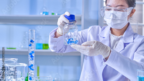 The promotional template of experiment theme for poster design, was shot from front view. A scientist hold a glass bottle contains gel balls in hand and clearly observing