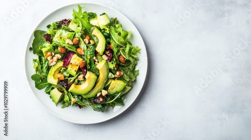 Fresh avocado salad with mixed greens and nuts in a white bowl