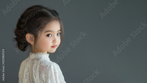 Chinese little girl wearing moroccan kaftan isolated on gray photo