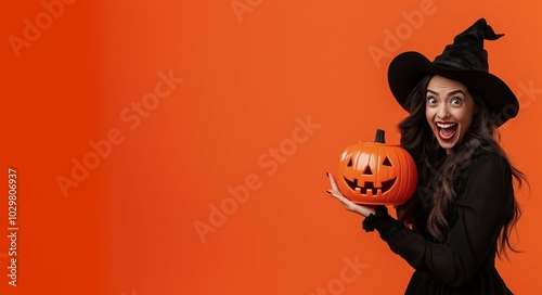 A person in black leather gloves wearing a pumpkin-head mask and a silver jacket, against an orange background photo