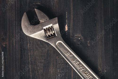 Adjustable wrench on wooden table. Heavy duty tool. Adjustable wrench on wooden table. Dark moody still life  photo