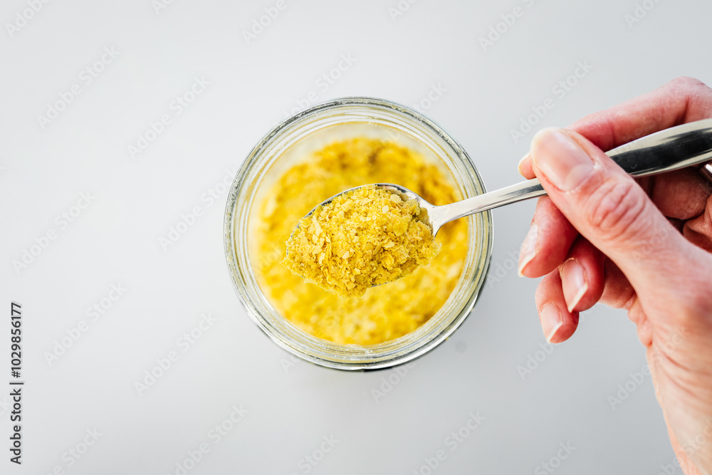 pantry staple close-up, spoonful of nutritional yeast over clear glass jar shot from above pantry staple close-up, spoonful of nutritional yeast over clear glass jar shot from above