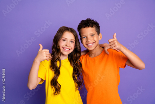 Photo portrait of cute little boy girl thumb up approve dressed stylish yellow orange clothes isolated on purple color background photo