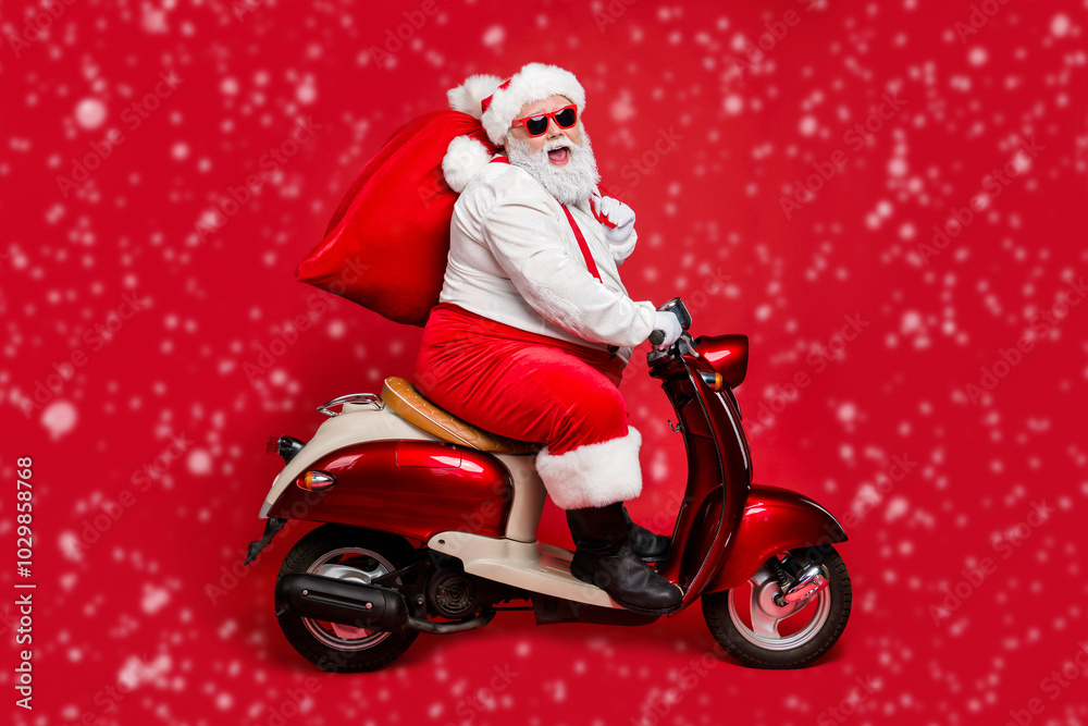 Profile side view portrait of nice bearded cheerful Santa St Nicholas father riding moped hurry up delivering large sack purchase concept isolated on bright vivid shine vibrant red color background Profile side view portrait of nice bearded cheerful Santa St Nicholas father riding moped hurry up delivering large sack purchase concept isolated on bright vivid shine vibrant red color background
