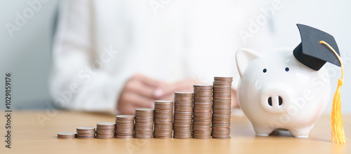 Money saving for Education, Scholarship, Student loan and debt and study future plan concept. Coins stack growing up with piggy and graduation hat on table