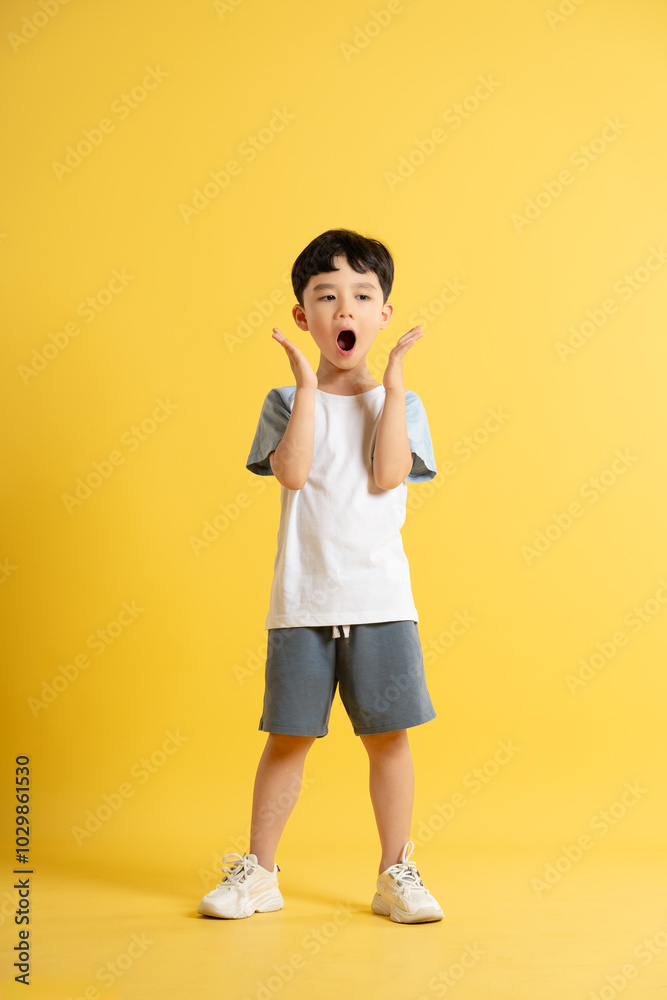 Full body image of asian kid boy wearing summer clothes posing on yellow background Full body image of asian kid boy wearing summer clothes posing on yellow background