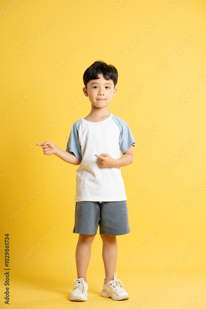 Full body image of asian kid boy wearing summer clothes posing on yellow background Full body image of asian kid boy wearing summer clothes posing on yellow background