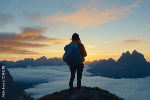 A girl with a backpack standing on top of the mountain, overlooking the valley below filled with fog at sunrise, concept of tourism, outdoor activities, hiking