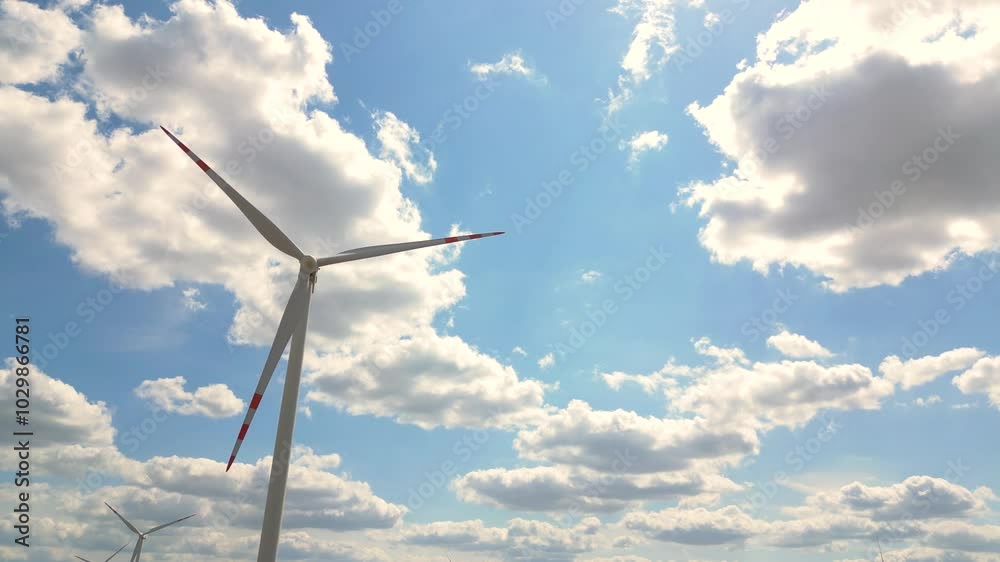 Exploring wind turbines against a blue sky with fluffy clouds during midday in a scenic landscape Exploring wind turbines against a blue sky with fluffy clouds during midday in a scenic landscape