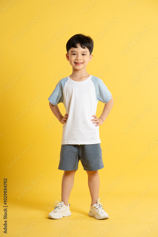 Full body image of asian kid boy wearing summer clothes posing on yellow background Full body image of asian kid boy wearing summer clothes posing on yellow background