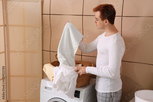 Young man sorting laundry i...