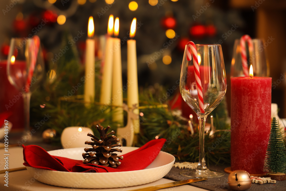 Christmas table setting with burning candles in room at night, closeup Christmas table setting with burning candles in room at night, closeup