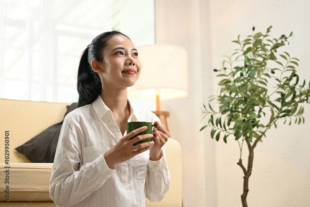 A woman is sitting on the floor with a green mug in her hand. A woman is sitting on the floor with a green mug in her hand.
