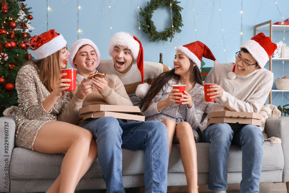 Obraz premium Group of young friends with pizza celebrating Christmas at home party