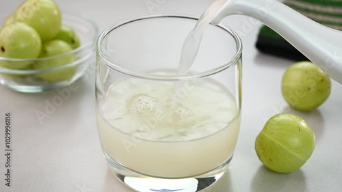 Serving amla juice also called as Indian gooseberry juice in a cup.