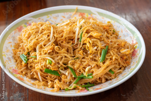 A plate of noodles with green and yellow vegetables on top