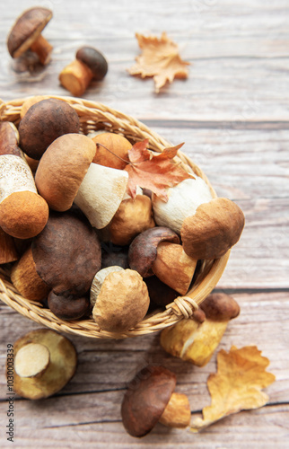 A rustic basket filled with assorted wild mushrooms and autumn leaves on a wooden table in a cozy setting
