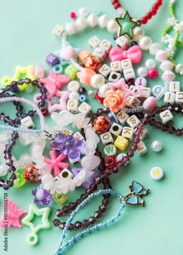Colorful beads and charms scattered on a blue surface, showcasing various shapes and colors, ideal for crafting and DIY jewelry projects