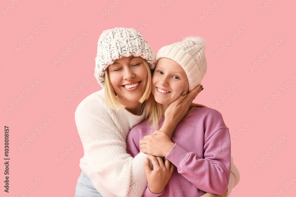 Beautiful woman with her cute daughter in stylish sweaters and hats on pink background Beautiful woman with her cute daughter in stylish sweaters and hats on pink background