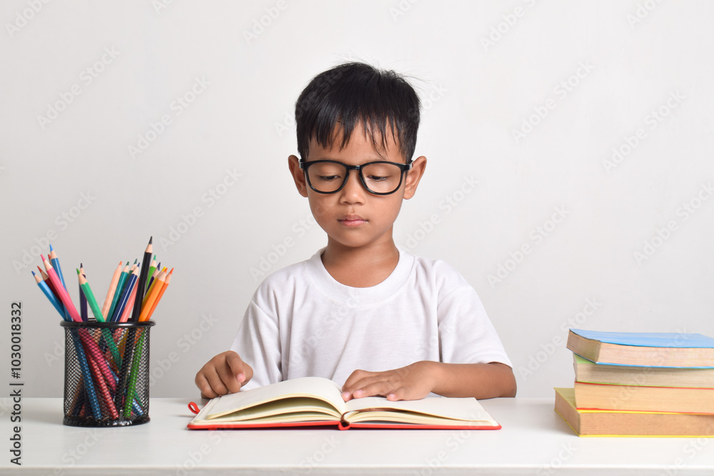Portrait of an Asian boy studying seriously looking at a book isolated on white background Portrait of an Asian boy studying seriously looking at a book isolated on white background