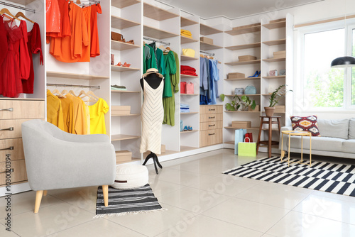 Interior of boutique with colorful clothes, mannequin and armchair