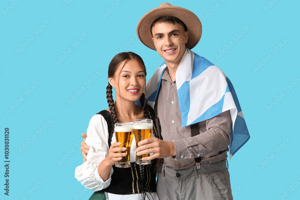 Young couple in traditional German clothes with glasses of beer and flag of Bavaria on blue background. Octoberfest concept Young couple in traditional German clothes with glasses of beer and flag of Bavaria on blue background. Octoberfest concept