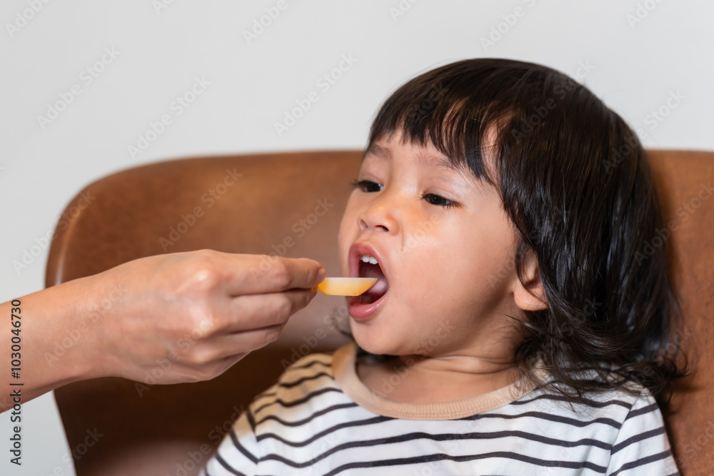 mother feeding liquid medicine to sick toddler baby with spoon mother feeding liquid medicine to sick toddler baby with spoon