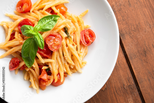Primo piano di un piatto di trofie condite con pomodorini, olio di oliva e basilico, dieta mediterranea 
